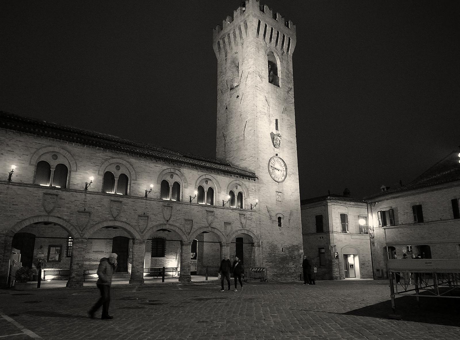 La Torre civica illuminata e la loggia del Palazzetto dei Priori in Piazza del Comune, in bianco e nero